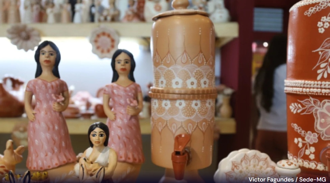 Peças de artesanato em barro expostas em prateleira, incluindo esculturas de mulheres com vestidos rosas e filtros de barro decorados com desenhos brancos. Crédito da foto: Victor Fagundes / Sede-MG